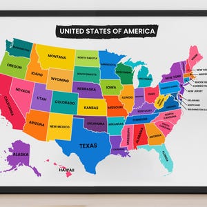 May include: A framed wall map of the United States of America featuring a colourful, multi-coloured design where each state is filled with a distinct solid colour. The title UNITED STATES OF AMERICA is printed in white text on a black background.