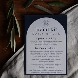 May include: A blue and white card with the text "facial kit DAILY RITUAL" and instructions for a daily skincare routine. The instructions include steps for "upon rising" and "before sleep".