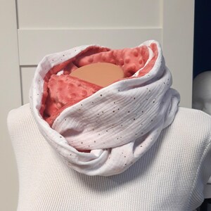 Peut inclure: Une écharpe infinie blanche et corail avec des paillettes dorées. L'écharpe est faite d'un tissu doux et pelucheux et est réversible.