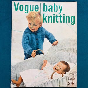 May include: Vintage Vogue baby knitting magazine cover. The cover features a young child in a blue sweater and another baby in a bassinet. The magazine title is in green text. The background is a solid teal color.
