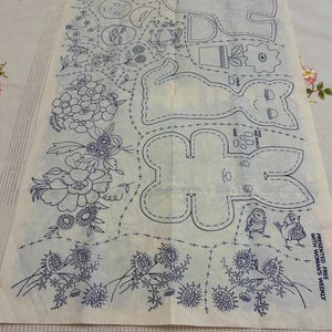 Könnte beinhalten: Ein Vintage-Schnittmusterbogen mit blauen Strichzeichnungen auf cremefarbenem Hintergrund. Der Bogen zeigt florale Designs, ein Kaninchen und andere skurrile Illustrationen. Der Text unten rechts lautet "PRESENTED FREE WITH WOMAN'S WEEKLY."