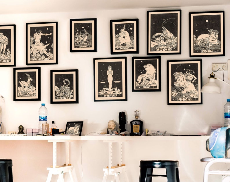 Puede incluir: Una pared blanca con 12 impresiones enmarcadas en negro de signos del zod&iacute;aco. Los signos est&aacute;n en orden de izquierda a derecha: Capricornio, Acuario, Piscis, Aries, Tauro, G&eacute;minis, C&aacute;ncer, Leo, Virgo, Libra, Escorpio, Sagitario. Las impresiones son todas en blanco y negro y tienen un estilo vintage.