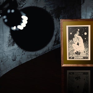 Puede incluir: Una ilustraci&oacute;n en blanco y negro enmarcada del signo del zod&iacute;aco Virgo. La ilustraci&oacute;n representa a una mujer con el pelo largo sosteniendo una estrella en su mano. El fondo es un cielo oscuro con estrellas y una luna creciente.