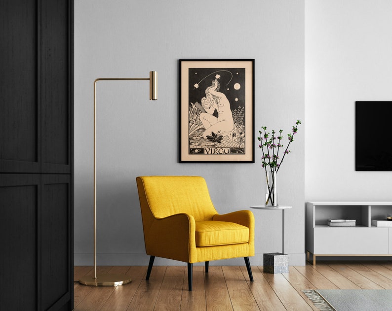 Puede incluir: Un p&oacute;ster enmarcado en negro con una ilustraci&oacute;n en blanco y negro de una mujer sentada con una estrella sobre su cabeza. El p&oacute;ster tiene la palabra "VIRGO" impresa en la parte inferior. El p&oacute;ster est&aacute; colgado en una pared blanca sobre un sill&oacute;n amarillo.