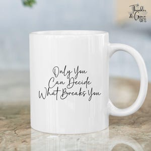 May include: White ceramic mug with a curved handle. The mug features the text "Only You Can Decide What Breaks You" in a black, cursive font. The mug has the "Thunder & Grace Gifts" logo in the upper right corner.
