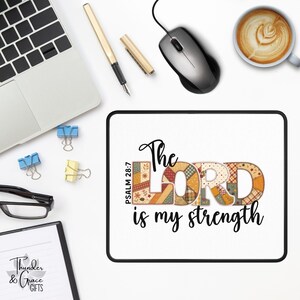 May include: A square white mousepad with a black border featuring the text The LORD is my strength and Psalm 28:7. The word LORD is filled with a multi-colored patchwork pattern of orange, brown, and cream floral and plaid fabric designs.