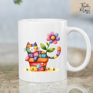 Puede incluir: Taza de cerámica blanca con un gato de retazos colorido en una maceta y una flor grande. El gato tiene un diseño de retazos en varios colores. La taza tiene un asa curva y el texto "Thunder & Grace GIFTS".
