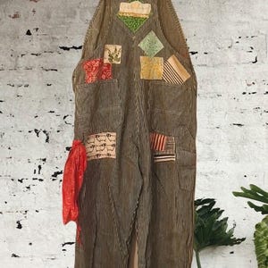 May include: Hickory stripe denim overalls featuring a variety of colorful fabric patches sewn onto the front. The patches include floral, geometric, and sheep-patterned designs. A bright red bandana is attached to the left side pocket area.