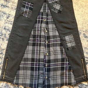 May include: A unique skirt design featuring a combination of dark gray denim and a gray, black, and purple plaid shirt. The denim sections have zipper details and plaid patches. The shirt is buttoned down the front.
