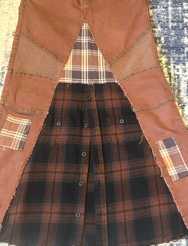 May include: A repurposed garment featuring brown denim pants with patchwork details and a button-down plaid shirt. The design incorporates various plaid patterns and textures, creating a unique, upcycled aesthetic. The garment has a deconstructed, handcrafted appearance.