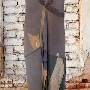 May include: A long, sleeveless dress in shades of gray, olive green, and beige. The dress features a V-neck, a zipper, and various fabric patches. The dress has a unique, patchwork design.