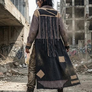 May include: A long, distressed denim coat featuring a leopard print upper section, black denim lower panels, and long black fringe detailing across the back. The garment includes various tan fabric patches, frayed edges, and a structured collar.