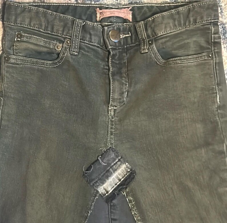 Puede incluir: Falda vaquera de lavado oscuro con un detalle de parche desgastado. La falda presenta un estilo cl&aacute;sico de cinco bolsillos, cierre de bot&oacute;n y cremallera, y trabillas para el cintur&oacute;n. El denim tiene un aspecto descolorido y desgastado.