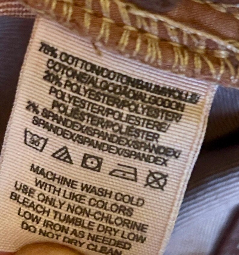 May include: Close-up of a fabric tag with text detailing the material composition: 78% cotton, 20% polyester, and 2% spandex. Washing instructions include machine wash cold with like colors, non-chlorine bleach, tumble dry low, and low iron.