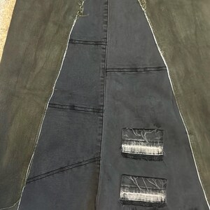 Puede incluir: Una falda vaquera patchwork con un dise&ntilde;o &uacute;nico. La falda presenta una combinaci&oacute;n de paneles de mezclilla gris oscuro y verde oliva, con costuras visibles y parches desgastados. La falda tiene una forma asim&eacute;trica distintiva.