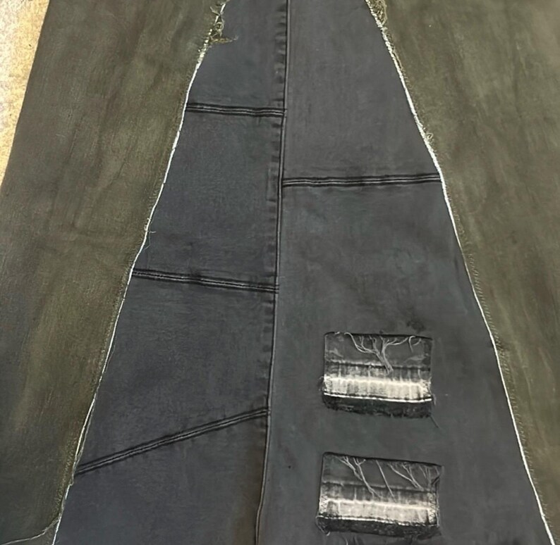 Puede incluir: Una falda vaquera patchwork con un dise&ntilde;o &uacute;nico. La falda presenta una combinaci&oacute;n de paneles de mezclilla gris oscuro y verde oliva, con costuras visibles y parches desgastados. La falda tiene una forma asim&eacute;trica distintiva.