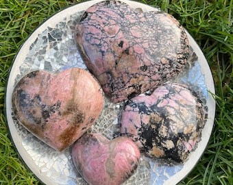 May include: Four pink and black heart-shaped stones on a silver mosaic plate. The stones are polished and have a natural, marbled appearance.