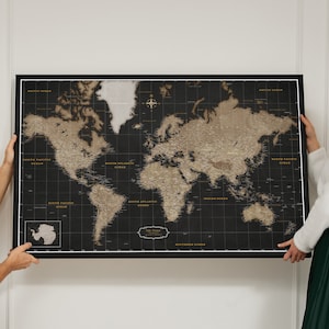May include: A framed world map with a black background and gold-colored continents. The map includes ocean names and is held by two people. The text "THE WORLD" is visible at the bottom of the map.