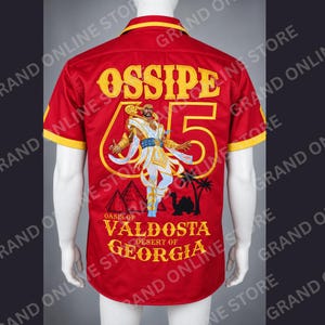 May include: A red short-sleeved button-down shirt with yellow trim. The back features a large graphic of a figure in white and gold robes, the text OSSIPE 65, and the words OASIS OF VALDOSTA DESERT OF GEORGIA with pyramids and palm trees.