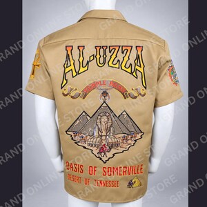May include: A tan short-sleeved button-down shirt featuring a large back graphic with the text AL-UZZA, TEMPLE NO. 169, OASIS OF SOMERVILLE, and DESERT OF TENNESSEE. The design includes a central sphinx, pyramids, camels, and an ankh symbol.