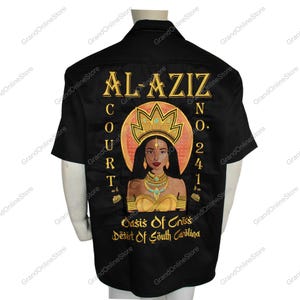 Könnte beinhalten: Schwarzes, kurzärmeliges Hemd mit Knöpfen und einer goldenen und orangenen Illustration einer Frau mit Krone und Schmuck. Der Text "AL-AZIZ COURT NO. 241 Oasis of Criss Desert of South Carolina" ist auf der Rückseite des Hemdes aufgedruckt.