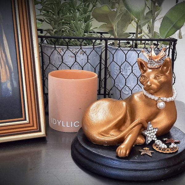 Golden vintage regal pussy cat sculpture with pearl necklace on striking black plinth with pretty delicate jewel details