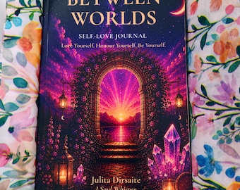 May include: A hardcover journal titled Between Worlds Self-Love Journal by Julita Dirsaite J Soul Whisper, featuring a vibrant purple and pink sunset archway illustration, nestled inside a box lined with floral patterned tissue paper.