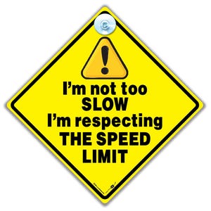 May include: Yellow diamond-shaped sign with a black exclamation point inside a triangle. The sign reads "I'm not too SLOW I'm respecting THE SPEED LIMIT".