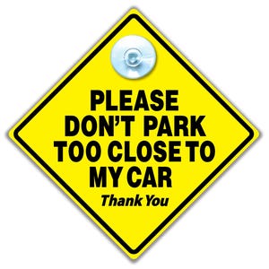 May include: A yellow diamond-shaped sign with black text reading "PLEASE DON'T PARK TOO CLOSE TO MY CAR Thank You." The sign has a black border and a clear suction cup. Designed to be attached to a car window, it warns other drivers.