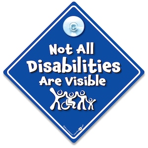 Könnte beinhalten: Blaues rautenförmiges Schild mit weißem Text: "Not All Disabilities Are Visible". Das Schild hat einen weißen Rand und einen Saugnapf oben. Unter dem Text befindet sich eine Grafik mit Strichmännchen, darunter eine Person im Rollstuhl.