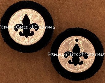 Puede incluir: Dos amuletos redondos de monedas de terciopelo negro con un centro de moneda plateada. Cada moneda tiene un recorte negro de flor de lis. El texto "PennyCutoutCharms" está impreso en la imagen.
