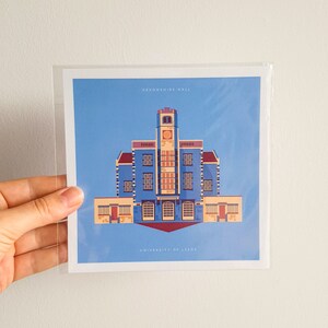 Op de afbeelding: Een blauwe en gele illustratie van Devonshire Hall aan de Universiteit van Leeds. Het gebouw heeft een klokkentoren en een rood dak.