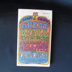 May include: A vintage paperback book titled "Great Wall Writing & Button Graffiti" by Robert Reisner. The cover features colorful text in orange, green, blue, and purple, with the words "Gents" and "Ladies" at the top. The book is a "NATION-WIDE SENSATION!"