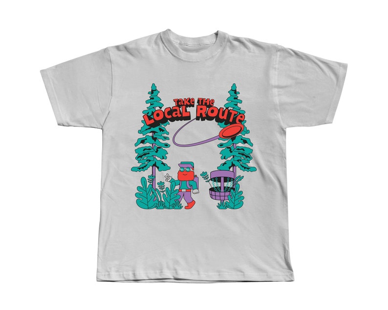 May include: White t-shirt with a graphic of a person throwing a disc in a forest. The graphic includes the text "Take the Local Route".
