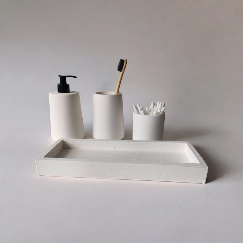 May include: White ceramic bathroom tray with a soap dispenser, toothbrush holder, and cotton swab holder. The tray is rectangular and has a smooth surface.