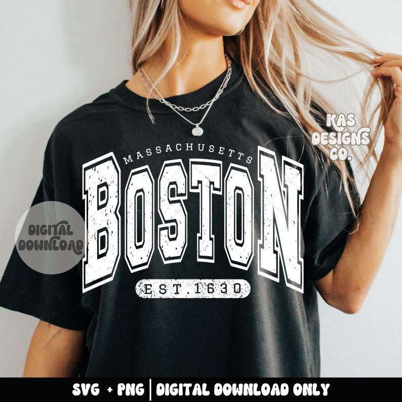 May include: A black t-shirt with a white graphic design that says "MASSACHUSETTS BOSTON EST. 1630". The graphic has a distressed, vintage look. The text "KAS DESIGNS CO." is in the top right corner of the design.