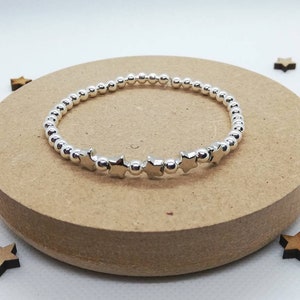 May include: A silver bracelet with small round beads and star-shaped charms.