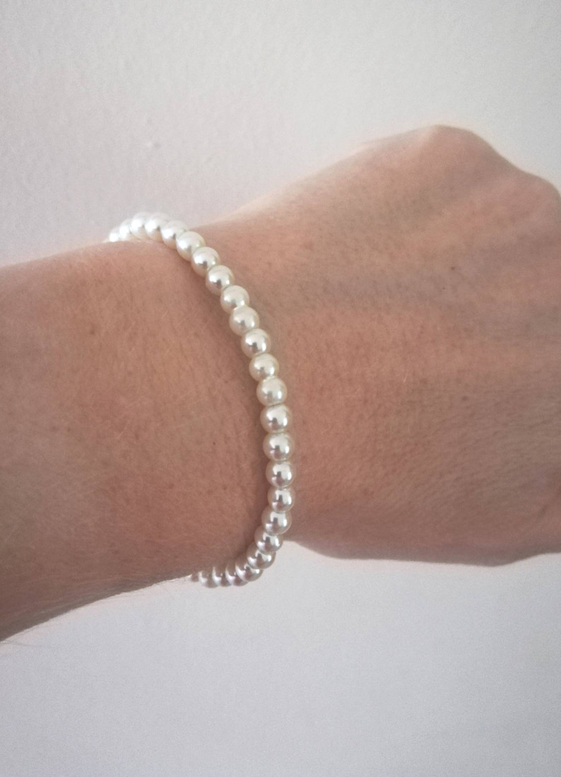 May include: A simple white pearl bracelet.