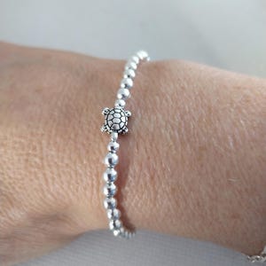 May include: A silver beaded bracelet with a small turtle charm.