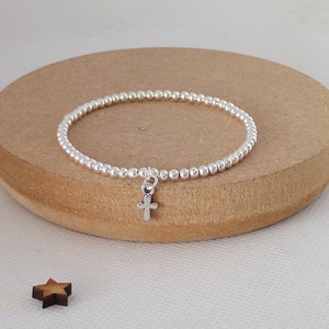 May include: A silver beaded bracelet with a small silver cross charm.