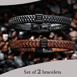 May include: Set of two leather bracelets with infinity symbol and personalised names. The top bracelet is black leather with the names "Noah" and "Isabelle". The bottom bracelet is brown leather with the names "Joshua" and "Ella".