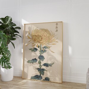 May include: A framed print of a yellow chrysanthemum flower with green leaves and a Japanese inscription. The print is on a cream background and has a gold frame.