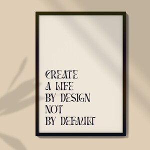 May include: A black framed print with the text "CREATE A LIFE BY DESIGN NOT BY DEFAULT" on a beige background.