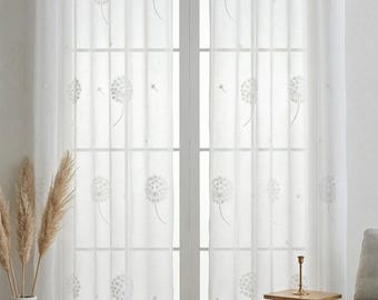 Könnte beinhalten: Ein Paar halbtransparente weiße Vorhänge mit einem zarten, gestickten Pusteblumenmuster in hellgrauem Garn. Die Vorhänge sind an einer silbernen Metallstange mit integrierten Ösen befestigt, wodurch der Stoff in weichen Falten herabfällt.