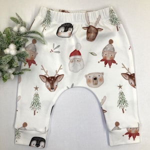 Puede incluir: Pantalones de beb&eacute; blancos con cintura el&aacute;stica, con un estampado repetido de personajes navide&ntilde;os como Pap&aacute; Noel, renos, ping&uuml;inos, elfos y osos. Los pantalones tienen un corte holgado y est&aacute;n hechos de tela suave.