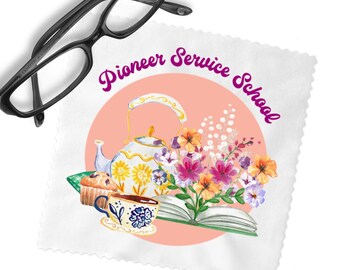 May include: A white square microfiber cleaning cloth featuring a pink circle with a watercolor illustration of a teapot, a teacup, a muffin, an open book, and colorful flowers. The text Pioneer Service School is printed in purple. Black glasses.