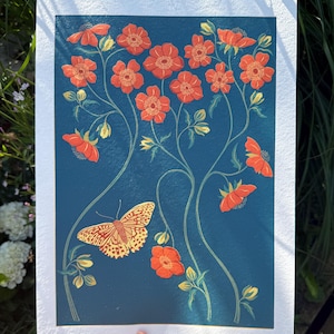 Puede incluir: Una lámina de arte rectangular sobre papel blanco texturizado con un fondo azul profundo, un patrón de flores naranjas sobre tallos verdes finos y una mariposa amarilla y naranja situada en la parte inferior izquierda de la composición.