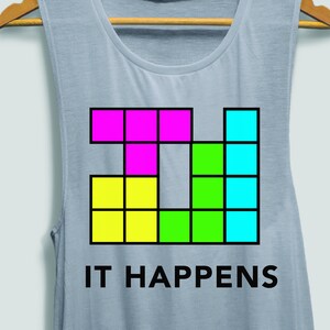 May include: A light blue tank top with a colourful block design and the text "IT HAPPENS".