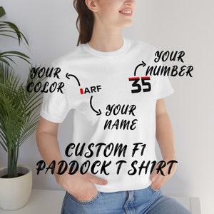 May include: White t-shirt with the text "CUSTOM F1 PADDOCK T-SHIRT" and space for personalisation. The text "YOUR COLOR" points to the left side of the shirt, "YOUR NAME" points to the bottom, "YOUR NUMBER" points to the right side, and "35" is written on the right side of the shirt.