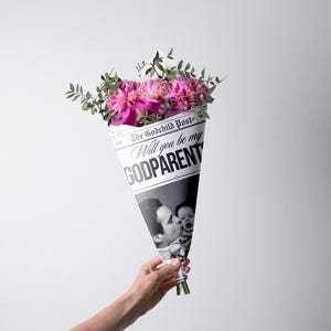 Może przedstawiać: Bukiet żywych różowych kwiatów i zieleni owinięty w stożek w stylu gazety. Stożek zawiera tekst "Will you be my GODPARENT" oraz czarno-białe zdjęcie rodzica i dziecka.
